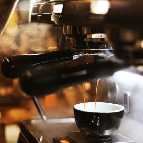 Close-up of espresso brewing process with modern coffee machine indoors.